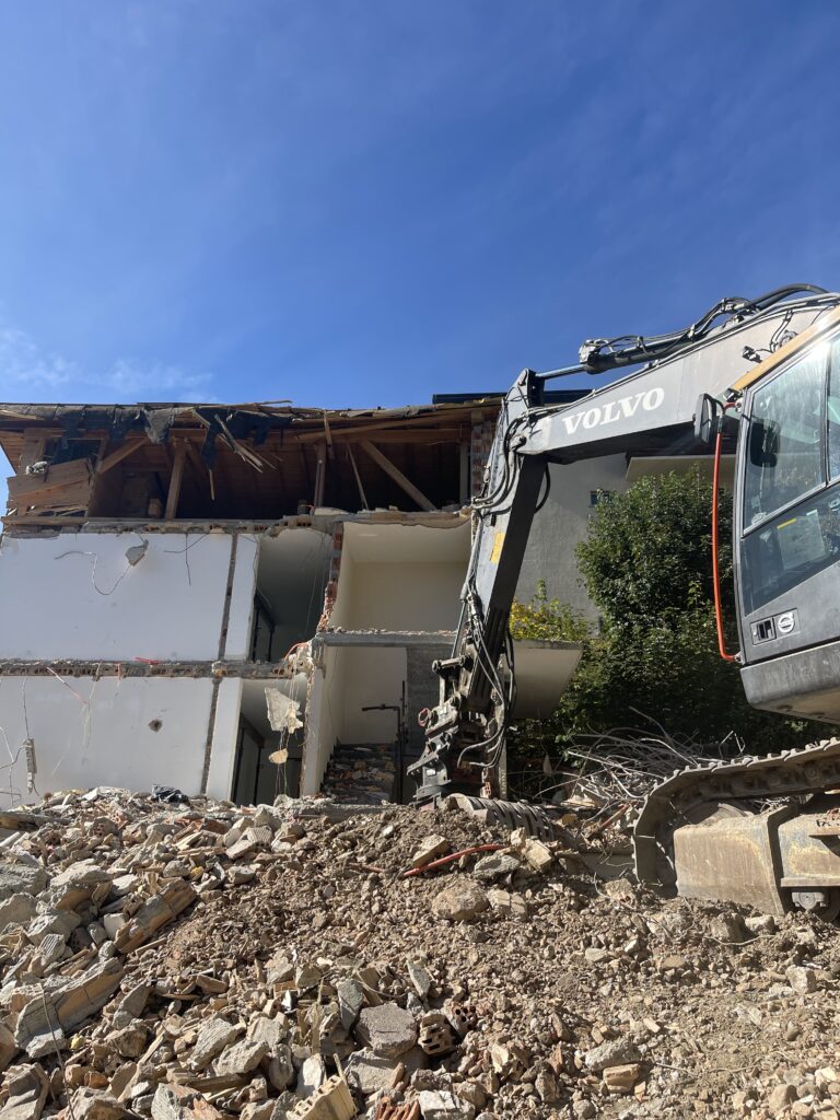 Pelle mécanique en train de démolir une maison, façade éventrée
