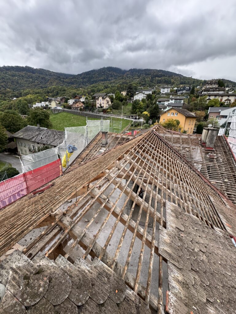 Démolition cheminée : toiture en cours de démontage, lattage à nu et filets de protection
