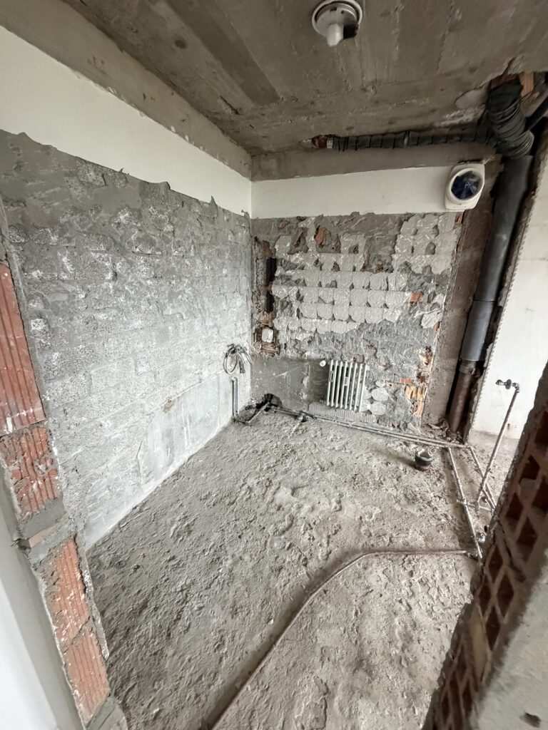 Salle de bain après démolition, murs bruts et sol à nu, dans un appartement à Crans-Montana